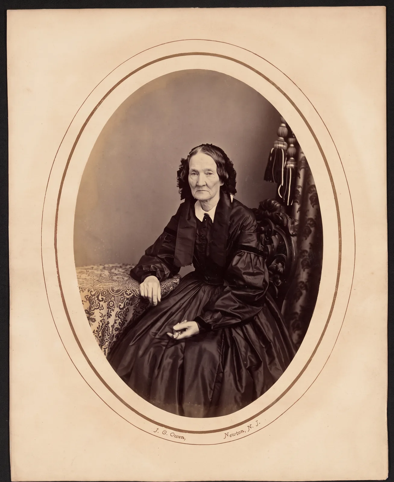 Restored: An elderly woman in a black dress, oval-matted portrait with stains