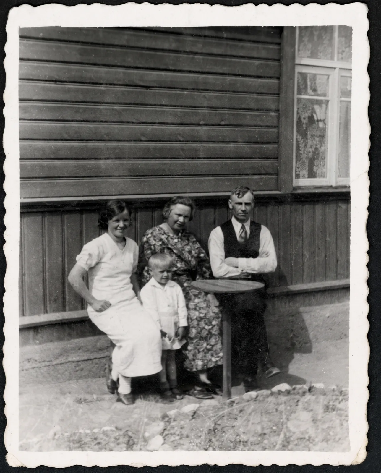 Restored: A family seated in front of a wooden house, scratched print